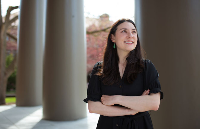 Alyssa Botelho, shot from the waist up in front of columns, looks off into the distance