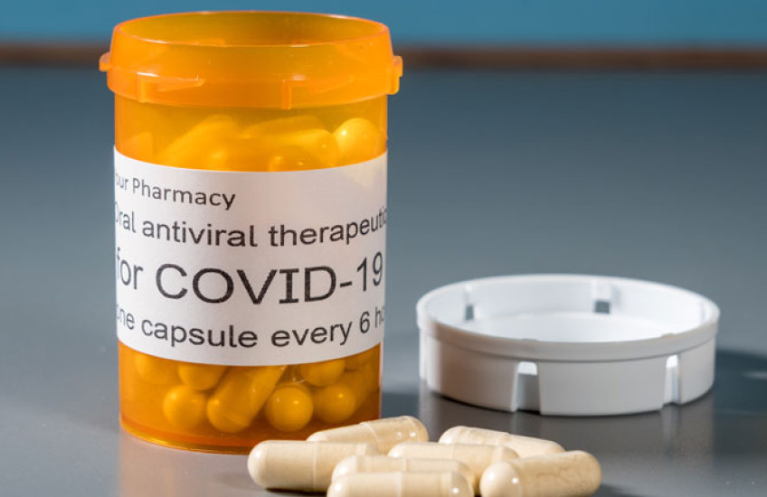 Image of a pill bottle that says COVID Rx with some pills near it