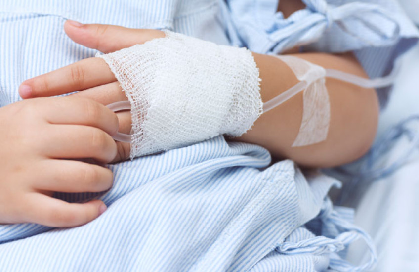 close up shot of a child's hands, one with an IV inserted 