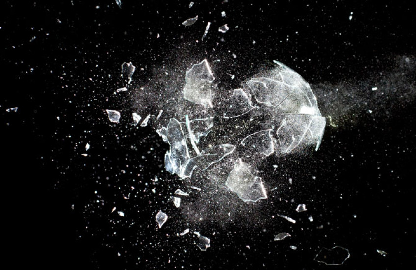 A piece of glass being destroyed against a black background