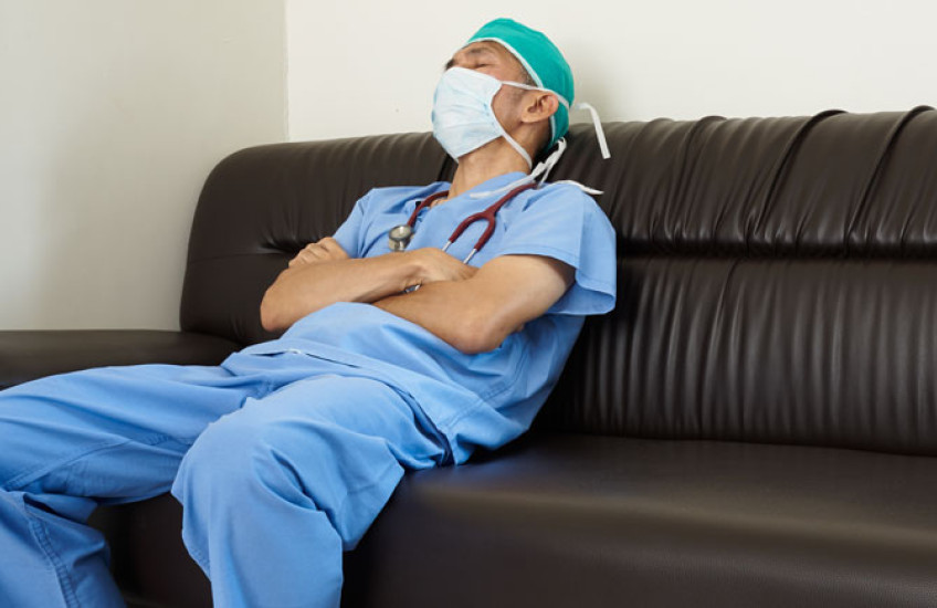 Doctor in blue scrubs dozing on a couch