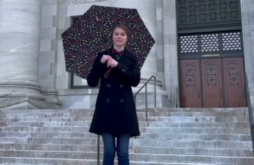 A women holding a polkadot umbrella stands in front of Gordon Hall