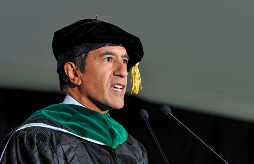 Photo of Sanjay Gupta in cap and gown delivering keynote address.