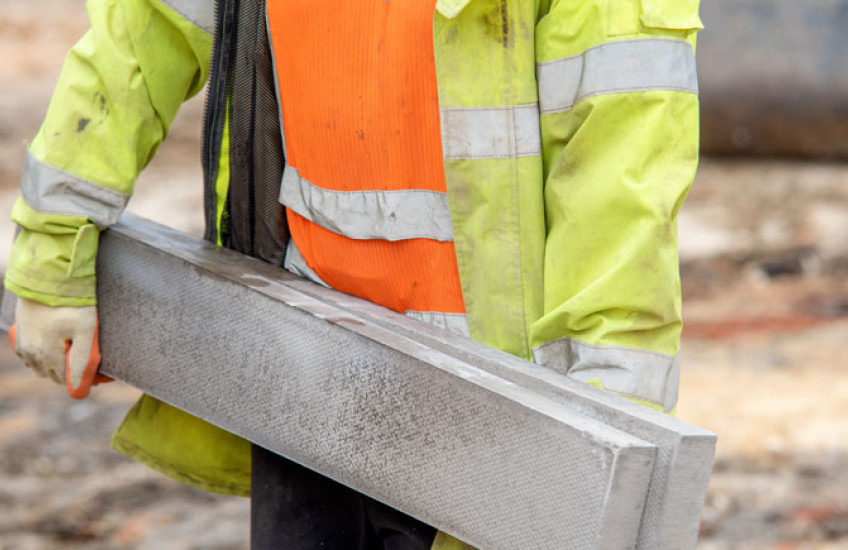 Photo of a construction worker carrying a large concrete beam 