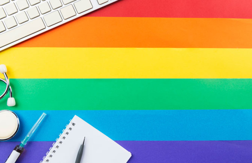 stethoscope, computer keyboard over pride colors