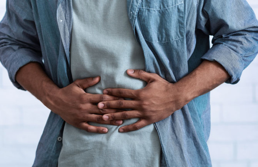 The torso of a person in a blue shirt with their hands over their stomach