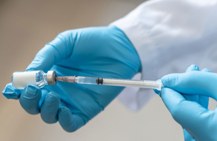 Blue-gloved hands holding a vaccine syringe