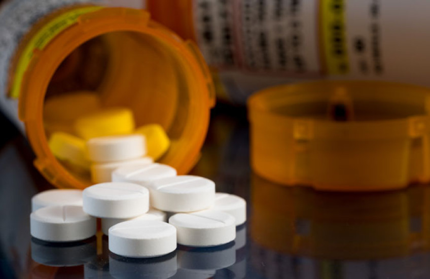 White pills spilling out of a prescription bottle 