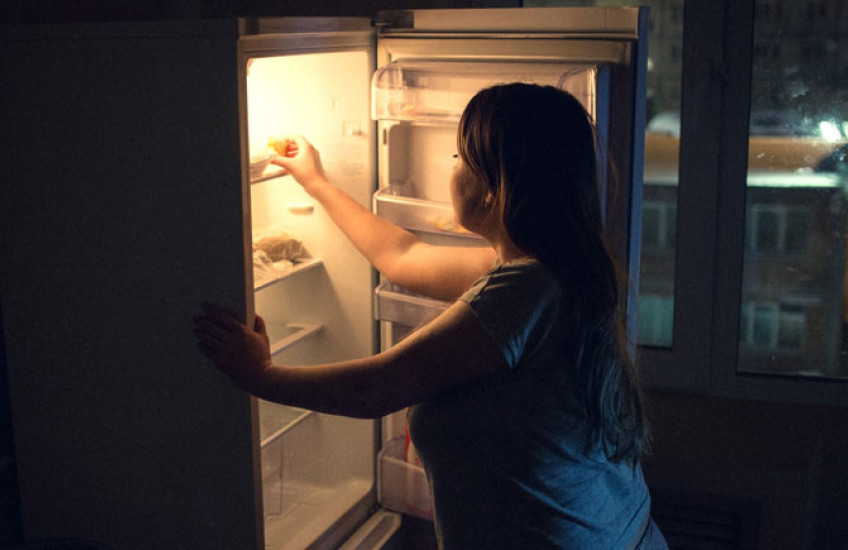 Photo image of woman getting something out of the refrigerator late at night