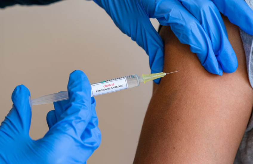 Glove hands administering a vaccine shot to an arm 