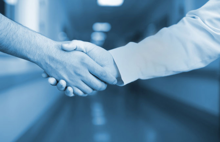 Photo illustration of two health care providers shaking hands in hospital hallway