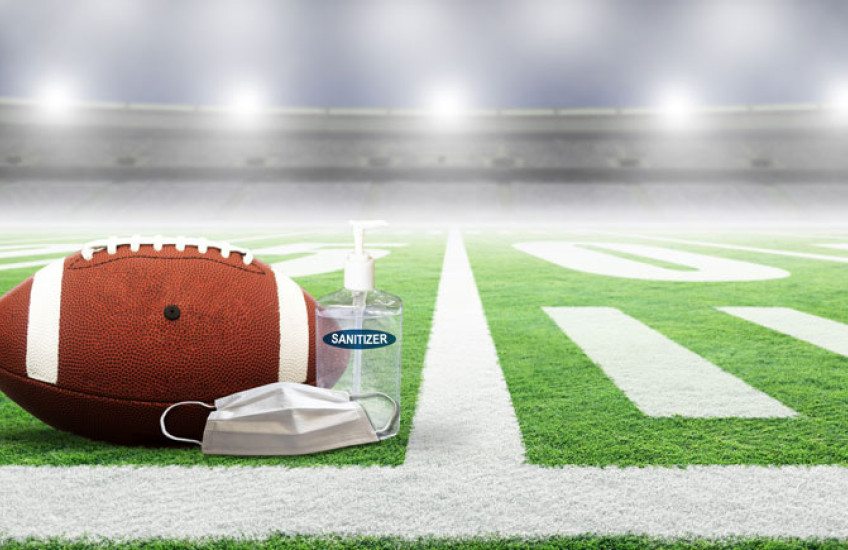 Photo of a football field with a ball, mask and sanitizer