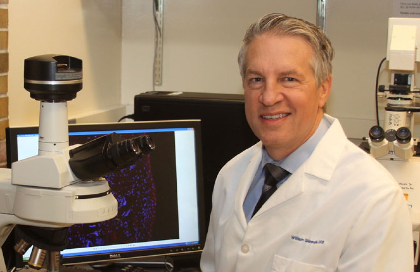 Photo of Giannobile in white lab coat at a microscope