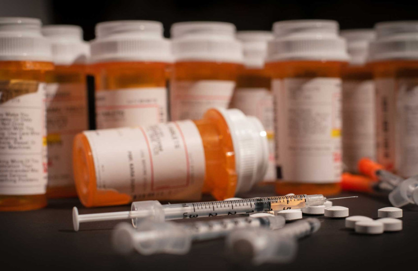 Photo of opioid pill bottles and a syringe