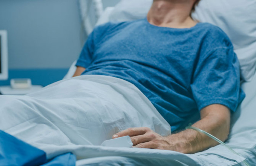 The torso of a patient lying in a hospital bed