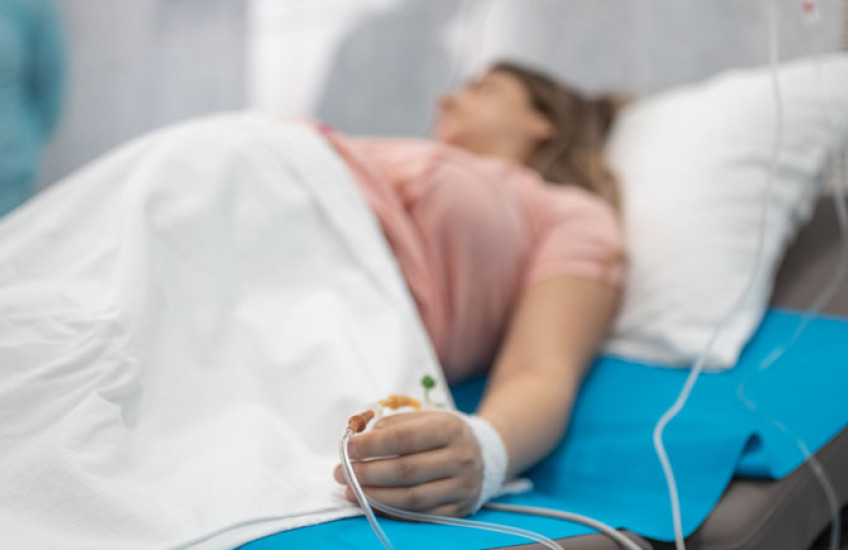 Out of focus image of a pregnant woman on a hospital bed with IV 