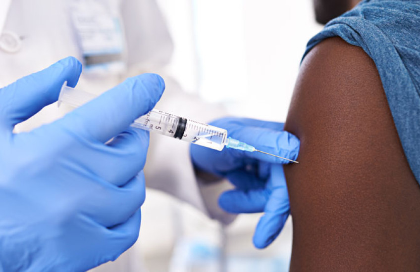 A closeup of a gloved healthcare provider injecting a vaccine into a patient's arm