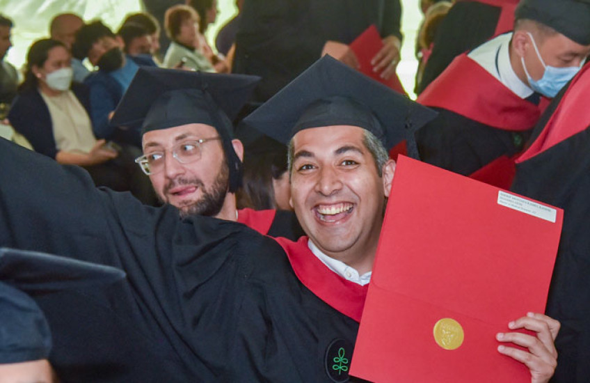 Photo of master's student smiling and holding diploma