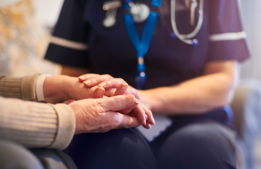 Stock image of caregiver with older patient - hands only