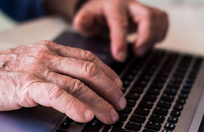 Photo of an older persons hands on a laptop keyboard 