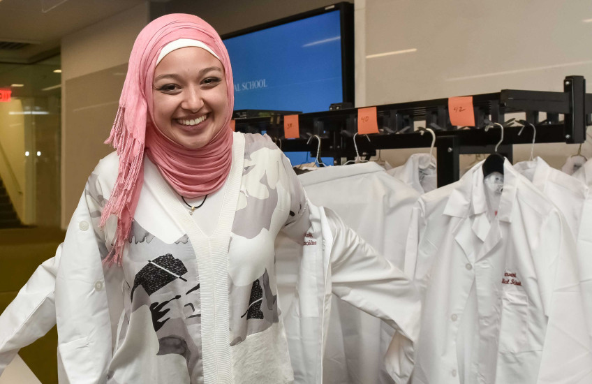 HMS Class of 2022 medical student donning her white coat. 