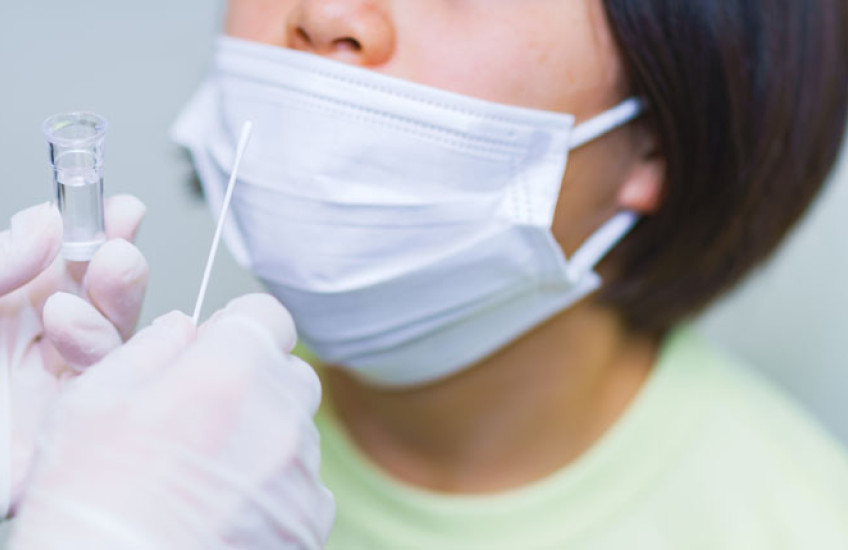 photo of a child with a mask about to get a nose swab for COVID