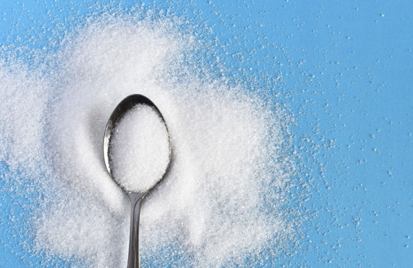 Photo of a spoon of sugar against a blue background