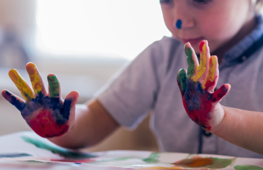 A young child's paint-covered hands.