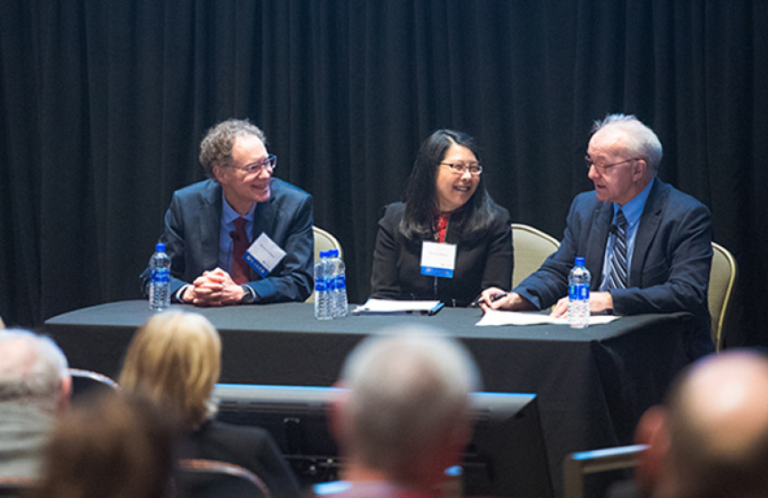 Three people at table in front of audience