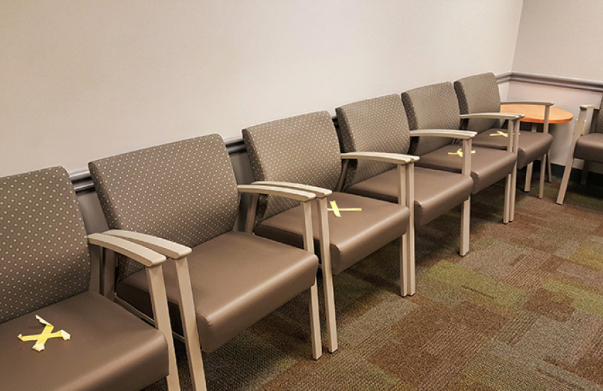 Empty chairs in waiting room, marked with X's for social distancing