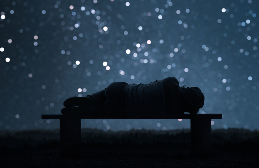 Photo illustration of a sleeping female form in silhouette with a backdrop of a night sky and stars
