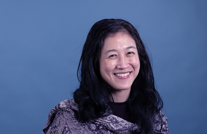Head shot of a smiling woman against a solid blue backdrop