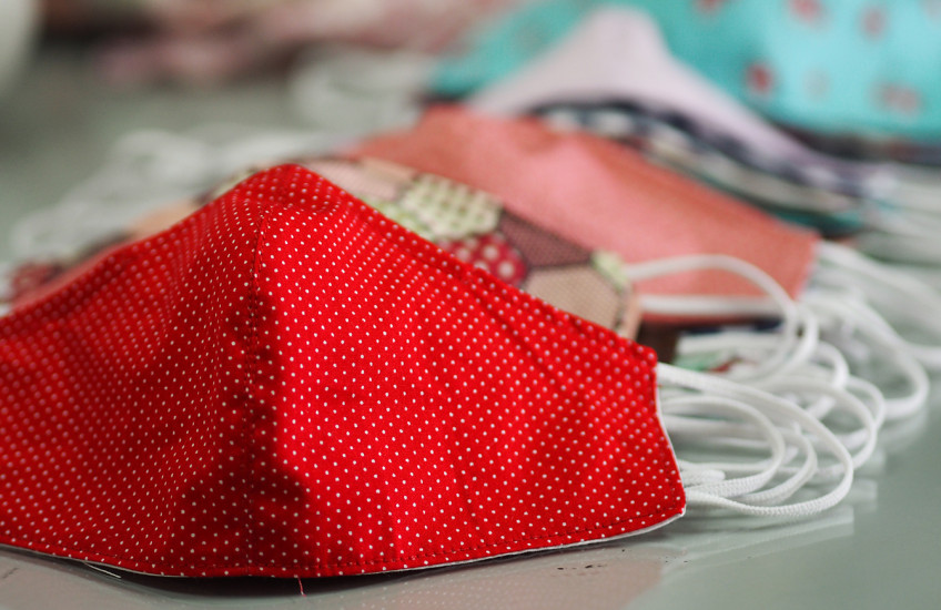 A group of colorful masks for protection from covid-19 sit on a desk.