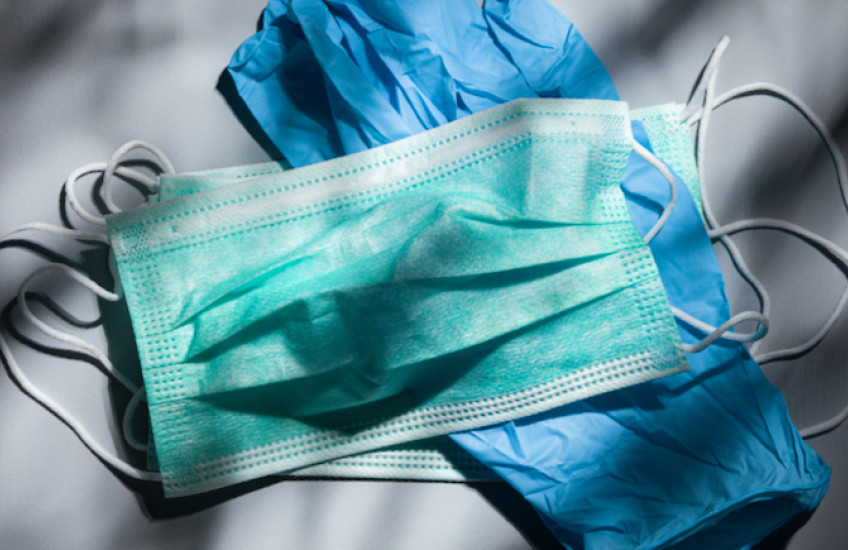 A mask and a pair f gloves on a table in dappled light