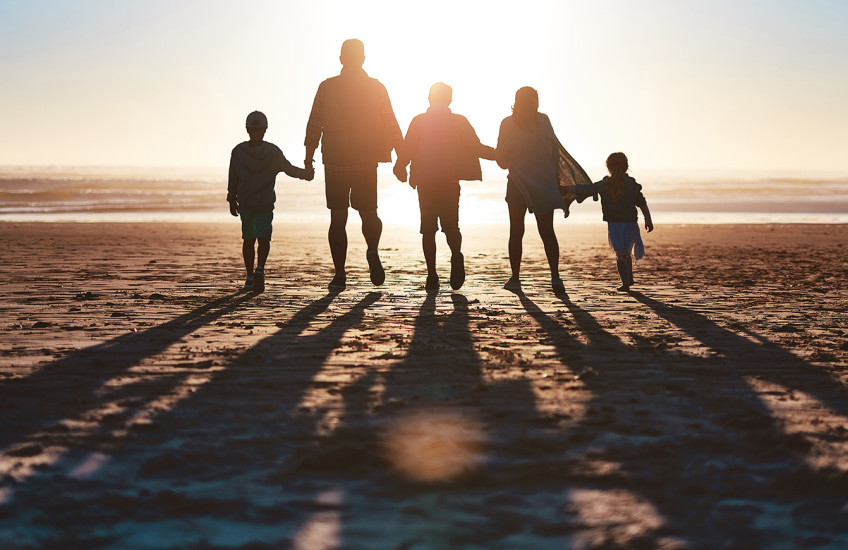 Silhouette of a family going for a walk together along the beach
