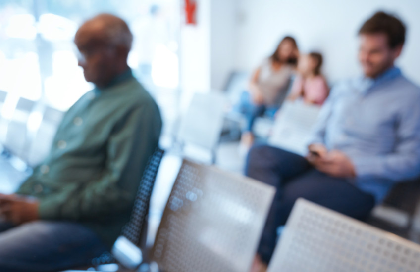 A blurry image of people in a waiting room.