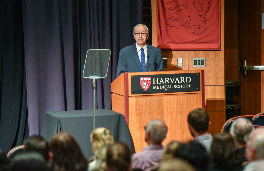 A person standing at a podium with a crowd of people watching