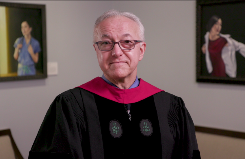 Dean Daley, wearing academic regalia, speaking in Gordon Hall