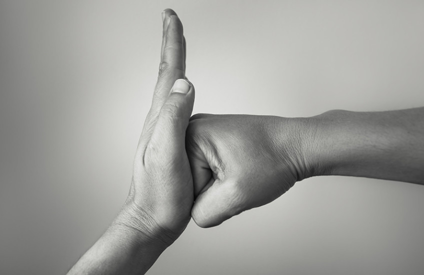 Black and white photograph of one hand stopping another hand from punching