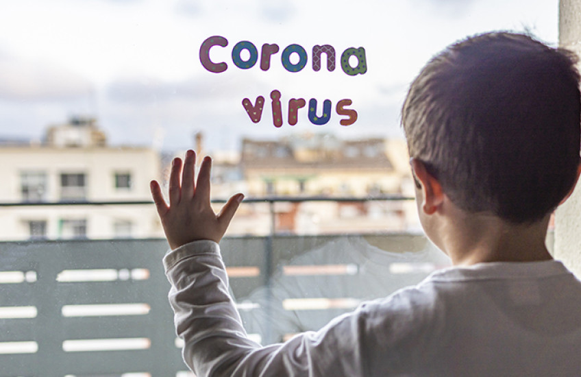 Child silhouetted against hospital window with letter-shaped magnets spelling out Corona virus