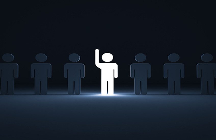 One glowing light man raising his hand among other dim people in the row on dark blue background with shadows