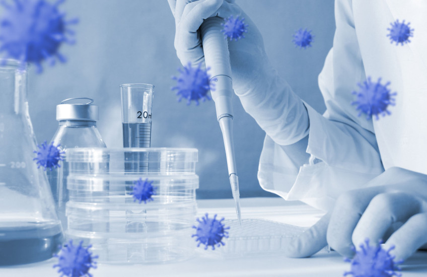 Photoillustration of coronavirus floating around lab equipment with person holding a pipette