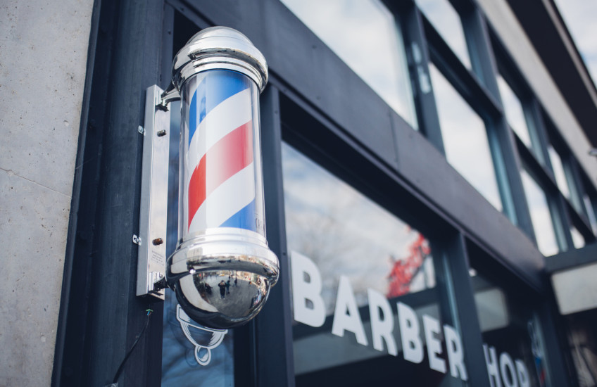 Photo of striped barbershop pole mounted on door of shop
