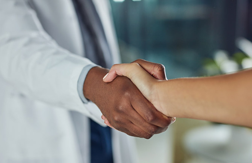 Doctor in a white coat shaking a patient's hand 