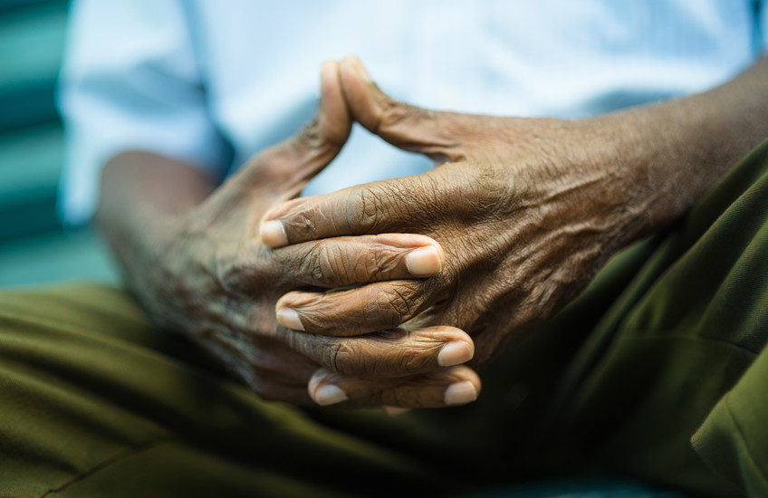 Closeup of hands of elderly Black man sitting on bench