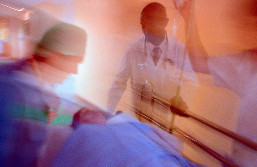 Motion blurred photo of hospital staff wheeling a patient on a gurney down a corridor