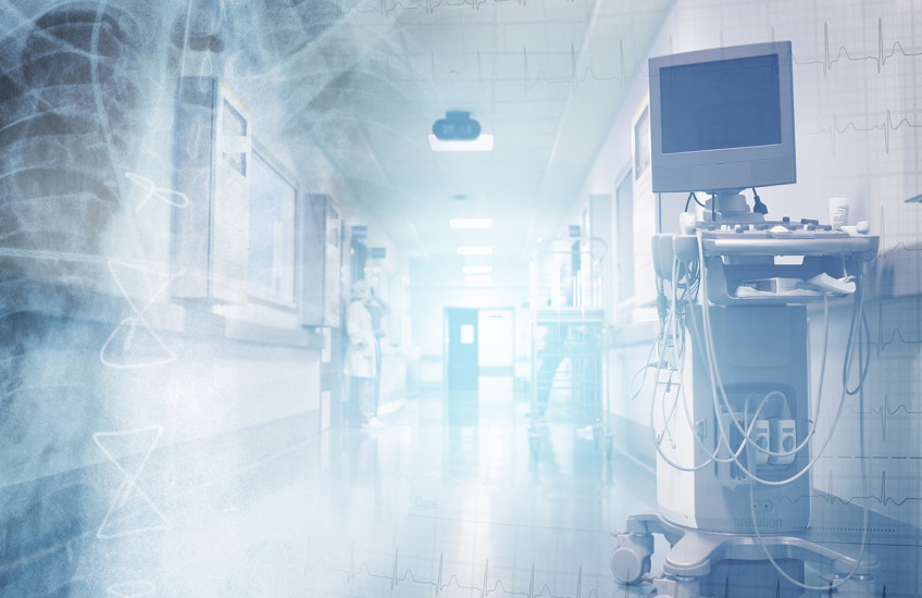 Translucent images of ECG chart and a chest x-ray image superimposed on a brightly lit hospital corridor