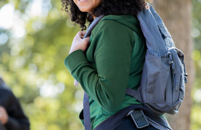 Young woman outdoors with backpack wearing a glucose monitor