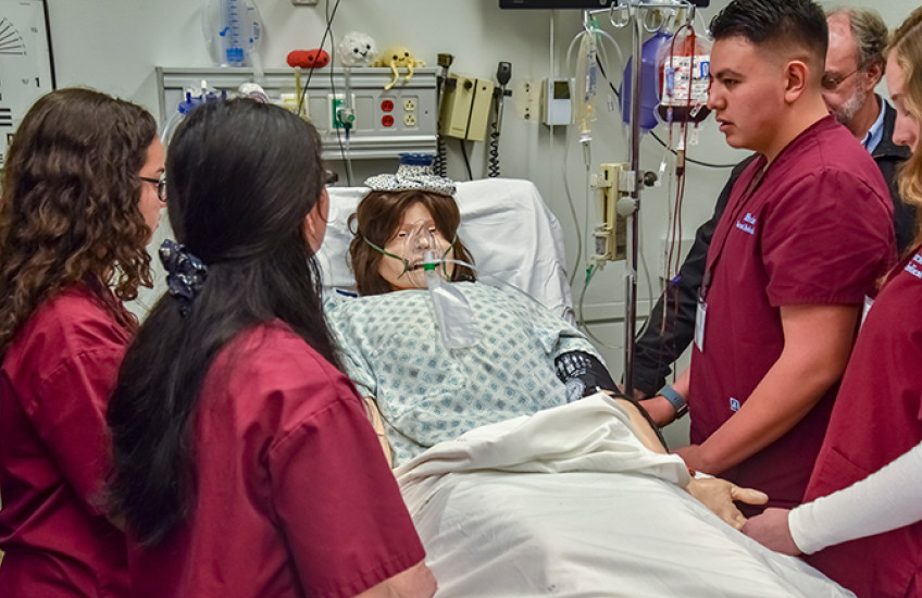 Students care for a “patient” in a MEDscience simulation. Image by Steve Lipofsky