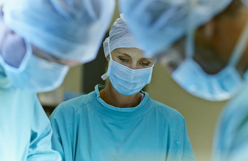 A team of masked surgeons performing surgery